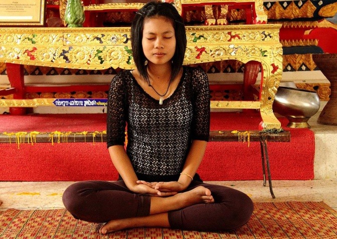 Frau macht Atemübung in Meditationshaltung