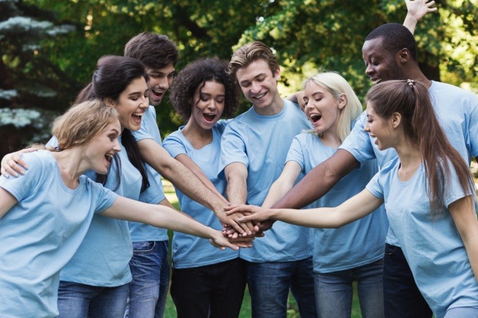 Eine Gruppe fröhlicher junger Menschen bereitet sich auf die gemeinnützige Arbeit in einem Park vor.