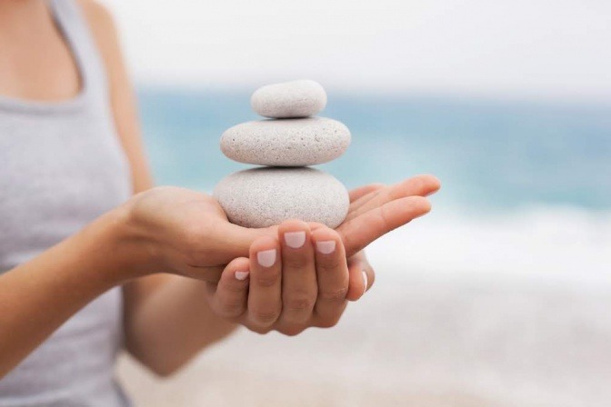 Frau mit Steinturm auf der Hand als Zeichen für Balance und Ayurveda