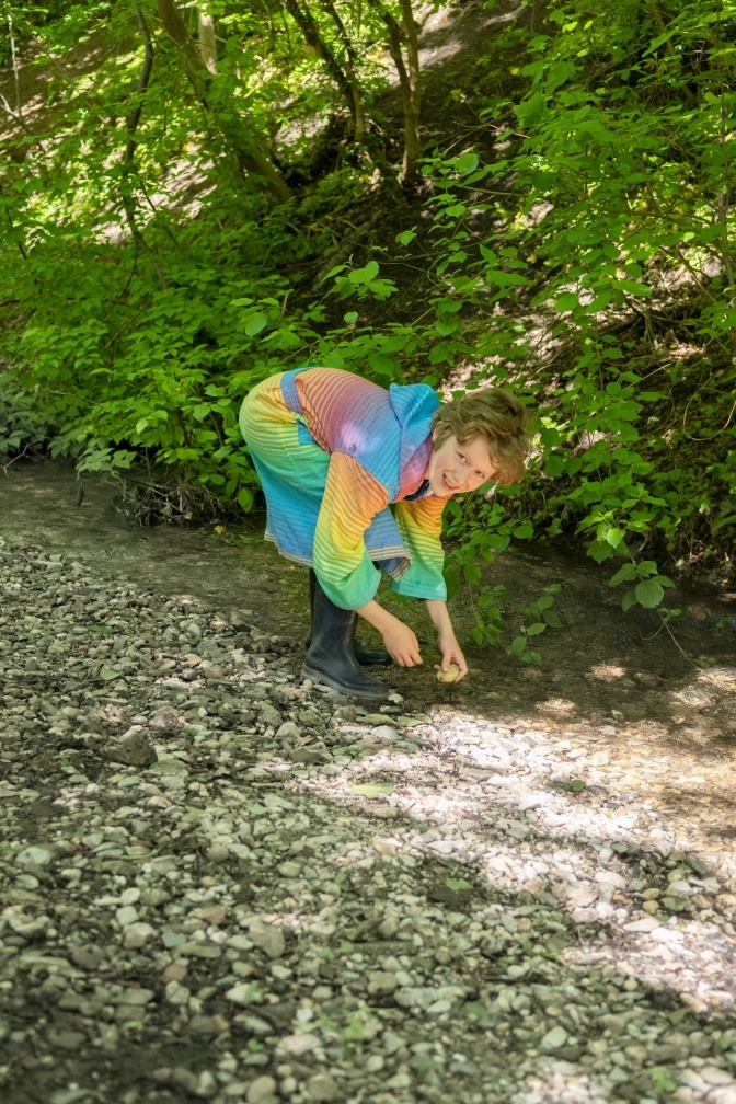 Kind mit Bademantel am Bach