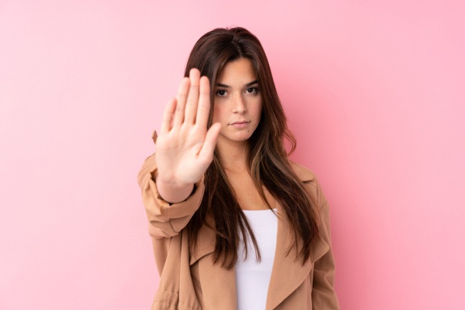 Junge Frau macht Stop-Geste mir ihren rechten Hand.