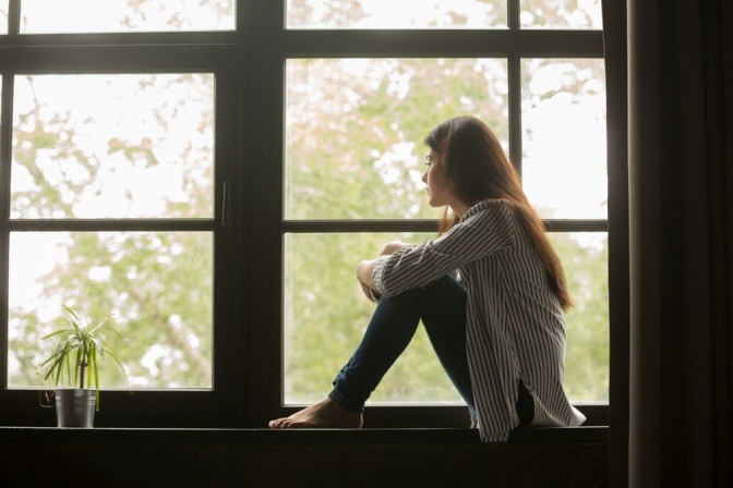Eine Frau am Fensterbrett, die ihr Bewusstsein verändern möchte