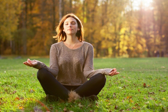 Eine Frau meditiert im Gras