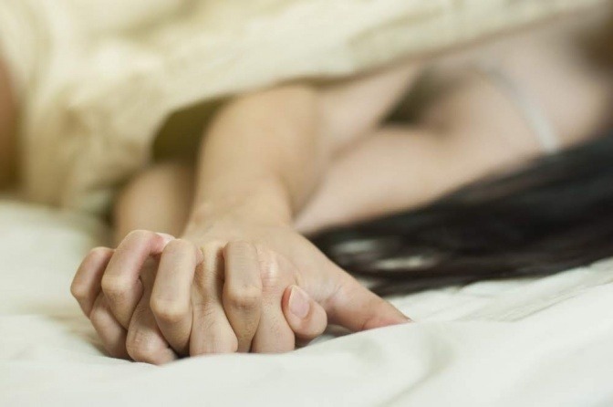 Hände von zwei Personen mit einer Beziehung oder Affaire im Bett