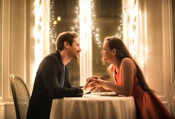Ein Paar sitzt händchenhaltend bei einem romantischen Dinner.