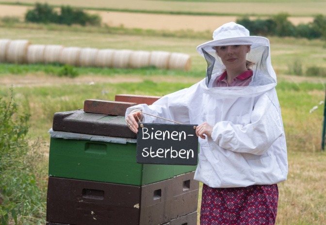 Eine Imkerin hält eine Tafel mit der Aufschrift Bienen-sterben