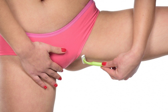 Eine Frau stellt ein Bein hoch um die Bikinizone zu rasieren