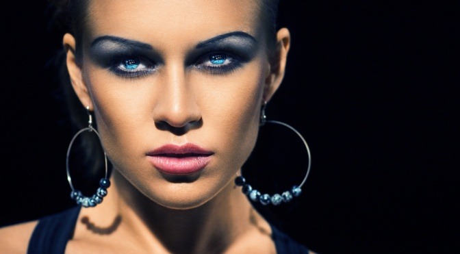 Eine Frau hat mit blauem Lidschatten Smokey Eyes geschminkt