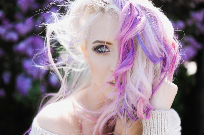 Eine Frau hat blonde Haare und lila und violette Strähnchen