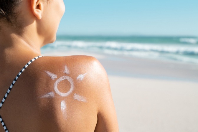 Frau mit einer Sonne aus Sonnencreme auf der Schulter