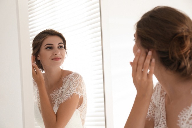 Frau mit Braut-Make-up steht vor dem Spiegel