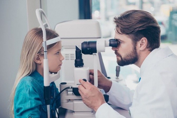 Ein Kind sitzt beim Augenarzt und lässt die Augen untersuchen