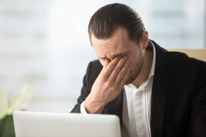 Ein Mann reibt sich die Augen als Schutz vor Burnout