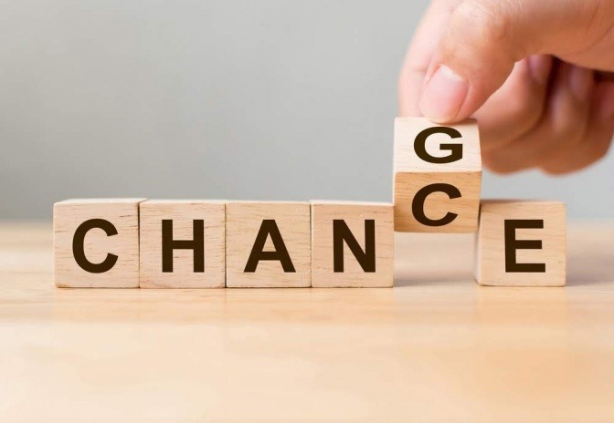 Das Wort Chance ist auf sechs Holzblöcken ausgeschrieben. Einer der Holzblöcke wird gerade umgedreht und man erkennt, dass auf der Rückseite der Buchstabe G ist, wodurch das Wort in den englischen Begriff change umgewandelt wird.