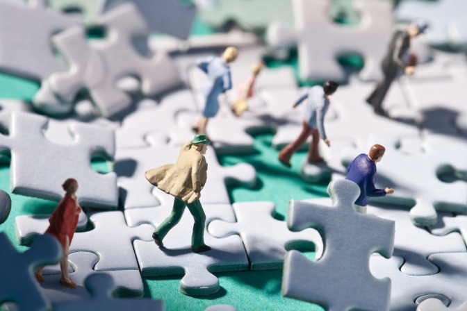 Leute gehen auf Puzzleteilen, es herrscht Chaos