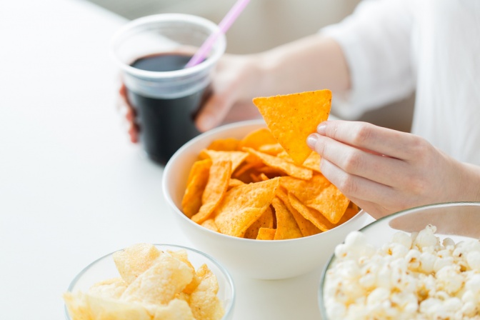 Eine Frau hält einen Becher Cola und Chips