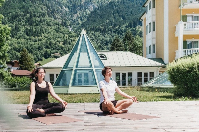 Zwei Frauen meditieren im Grünbereich des Hotel Alpenhaus Gasteinertal
