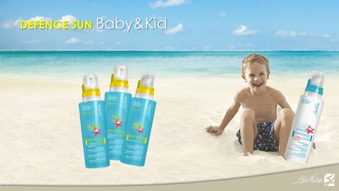 Ein Kind sitzt am Strand, daneben sind Sonnenschutz Produkte von Defence Sun Baby & Kid 