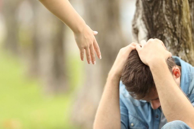 Eine Hand reicht zu einem depressiven Partner