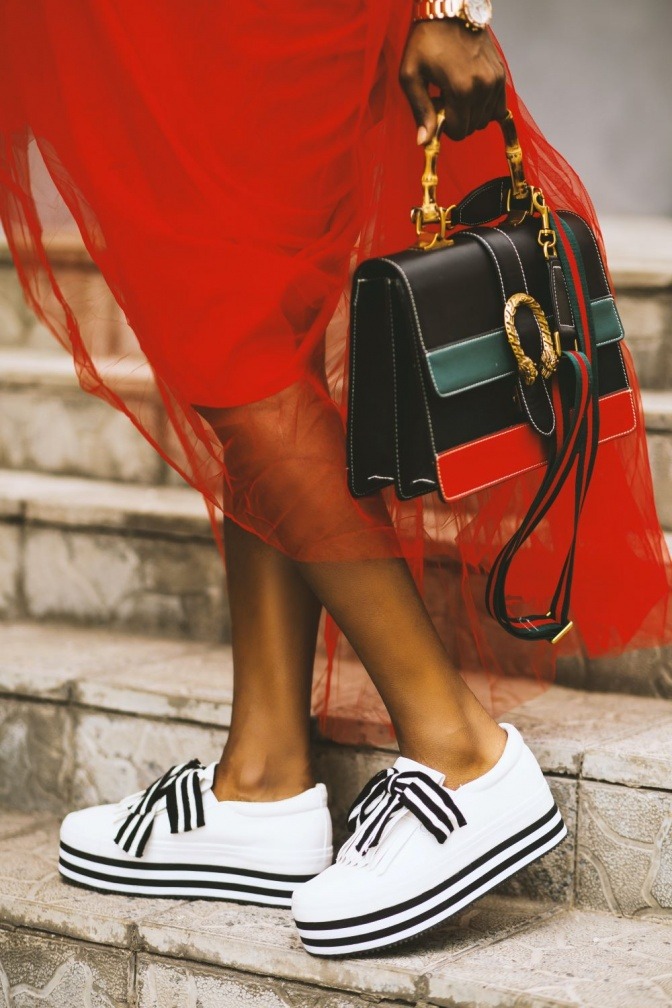 Eine Frau trägt eine schwarz-rote Designer-Handtasche