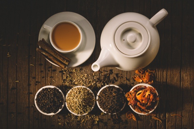 Eine Teekanne sowie verschiedene Gewürze stehen neben einer Tasse Detox Tee