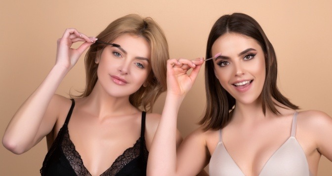 Zwei Frauen schminken dünne Augenbrauen