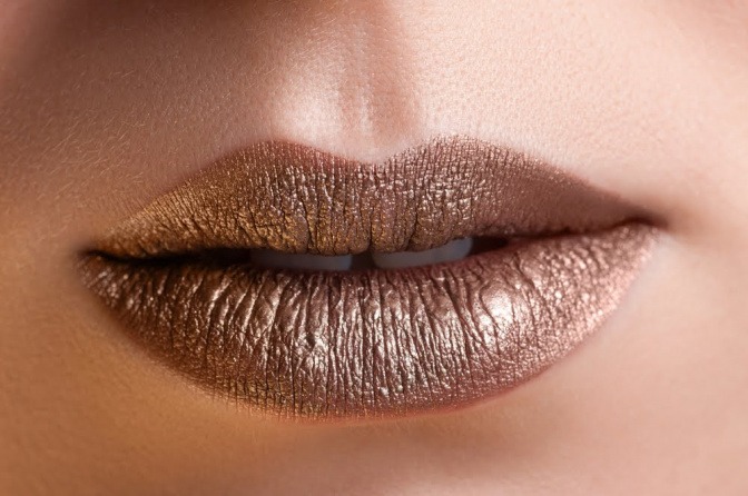 Eine Frau hat dunkle Haut und goldenen Lippenstift