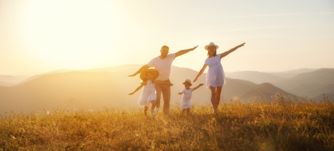 Ein Paar und ihre zwei Kinder toben auf einem Feld herum