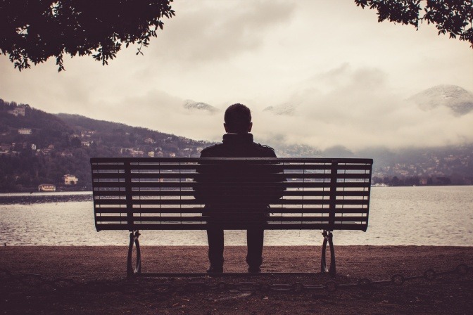 Ein einsamer Mann sitzt auf einer Bank