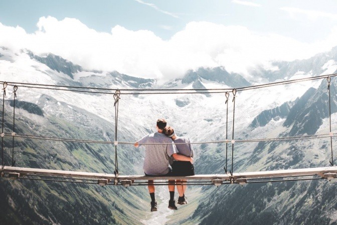 Frau und Mann sitzen auf einer Brücke über einem Abgrund