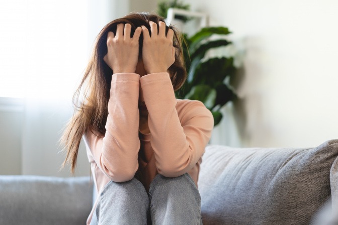 Frau sitzt verzweifelt auf dem Sofa.