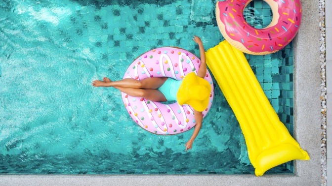 Frau auf einem aufblasbarem Donut im Schwimmbecken 