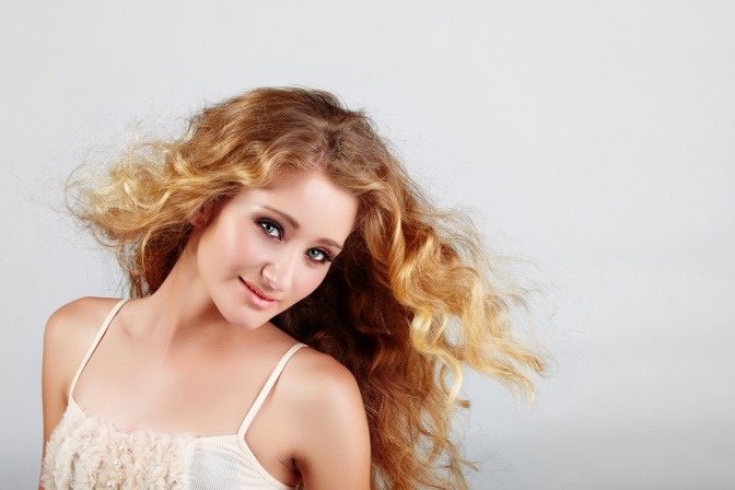 Eine Frau hat ihre Haare im Haarfarbentrend Erdbeerblond
