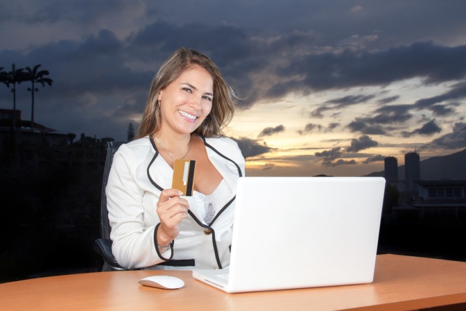 Eine erfolgreiche Frau mit Laptop und Kreditkarte sieht glücklich aus