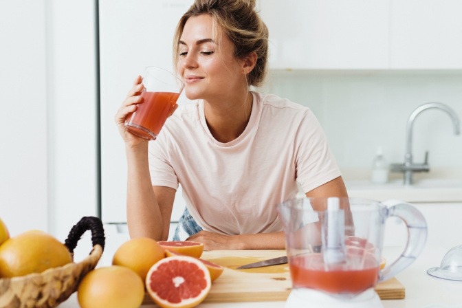 Frau trinkt Saft einer Grapefruit als Ernährung gegen Falten