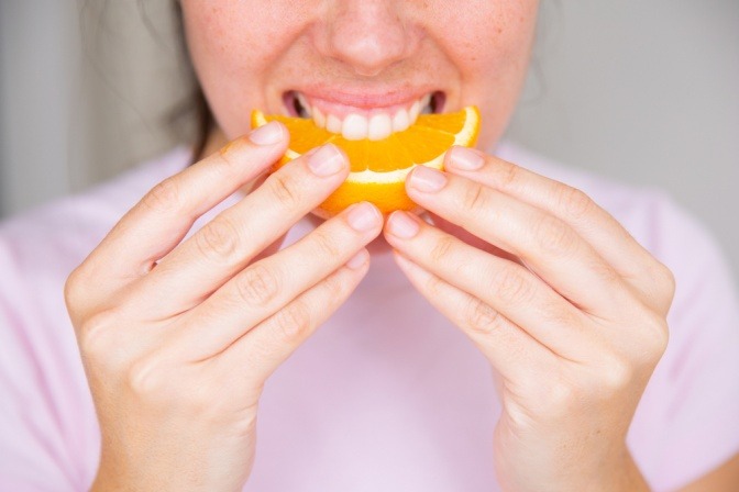 Frau beißt in ein Stück Orange