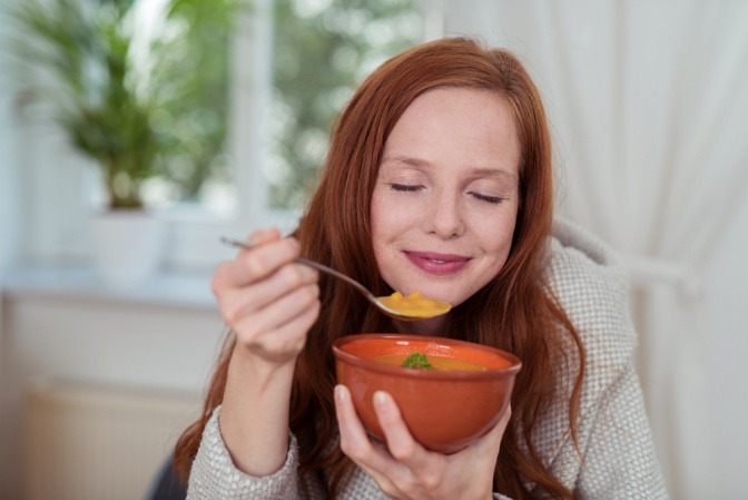 Frau genießt Kürbissuppe als Essen im Herbst