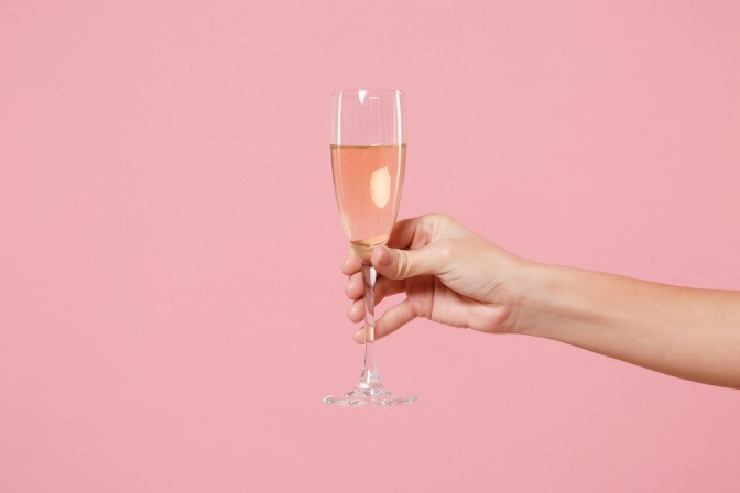 Glas Sekt in der Hand einer Frau.
