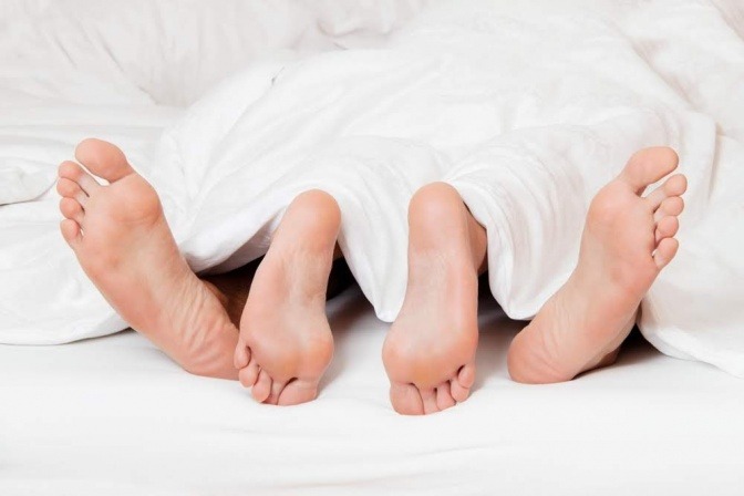 Die Fußsohlen eines Paares, das nebeneinander im Bett liegt.