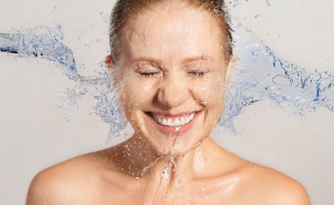 Frau spritzt Wasser in ihr Gesicht