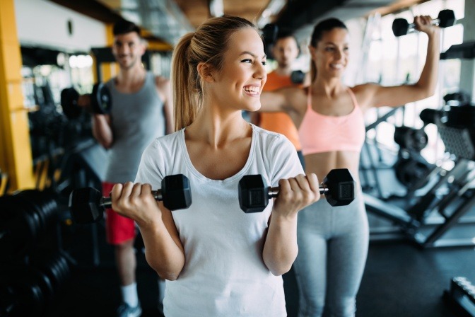 Eine Frau im Fitnesscenter hält Hanteln