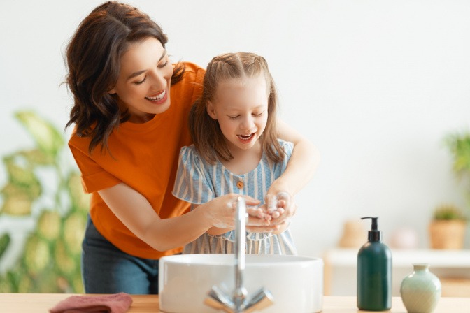 Mutter und Tochter waschen sich gemeinsam die Hände mit Flüssigseife. 