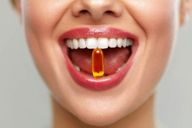 Eine Frau hat ein Nahrungsergänzungsmittel mit Folsäure im Mund
