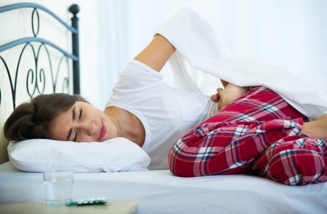 Eine Frau mit Bauchschmerzen liegt im Bett
