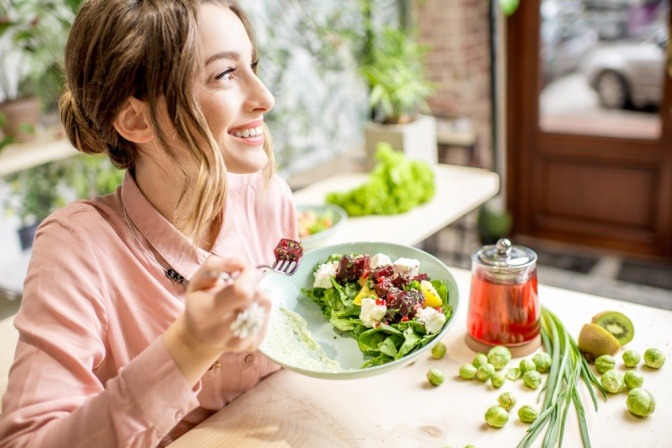 Gesunde junge Frau isst glücklich einen Salat