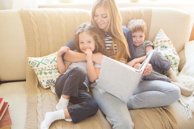 Frau mit zwei Kindern auf einem gemütlichen Sofa