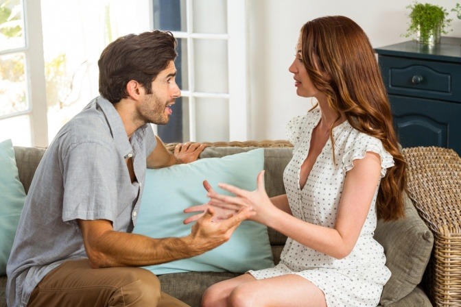Ein Mann und eine Frau sitzen im Wohnzimmer und streiten