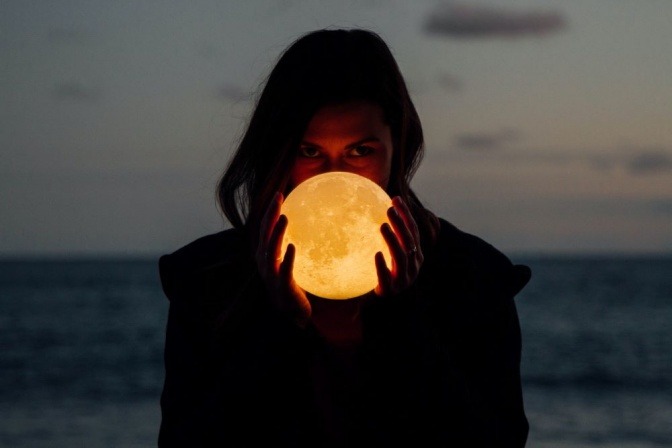 Eine Frau hält eine Kugel in den Händen, die an den Mond erinnert