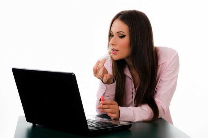 Eine Frau schminkt sich vor einem Laptop