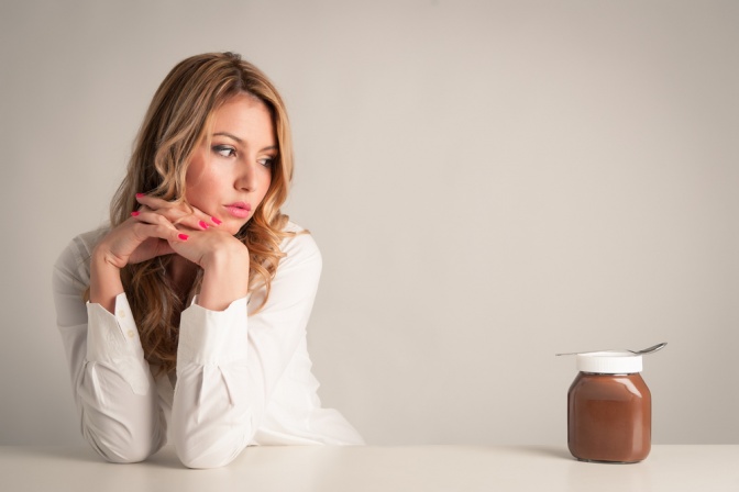 Eine Frau schaut auf ein Glas mit Schokoladecreme